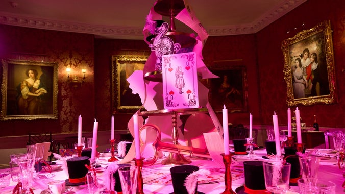 Round dining room table at Polesden Lacey dressed for Christmas with candles, black top hats and playing cards